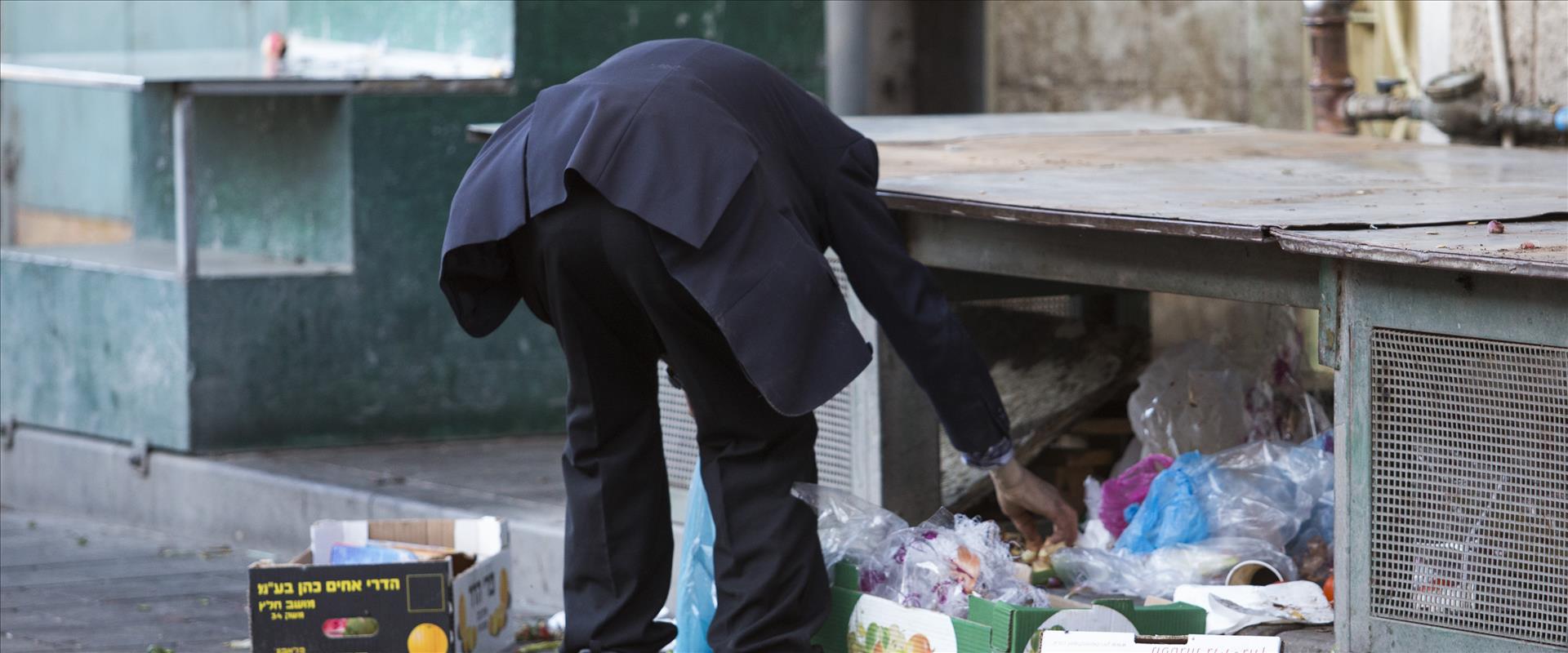 אדם מחטט באשפה בשוק מחנה יהודה בירושלים